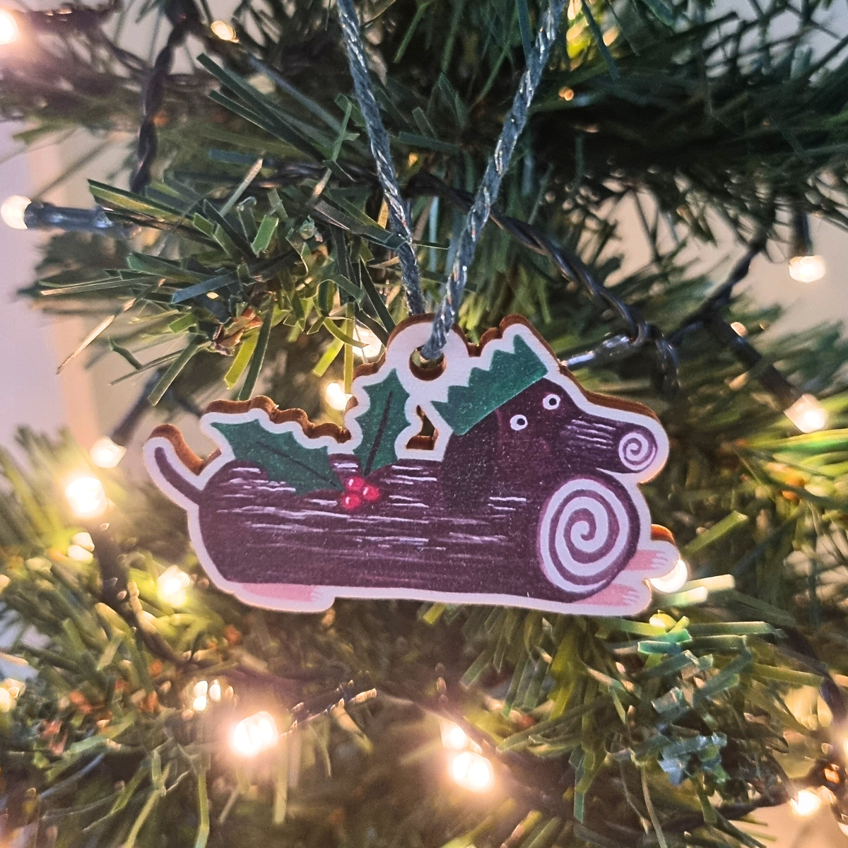 Decorative Christmas dog Christmas tree decoration shaped like a Christmas log with a Christmas party hat and holly leaves and berries.
